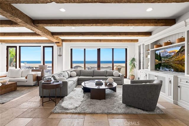 living room featuring stone tile flooring, beamed ceiling, and plenty of natural light