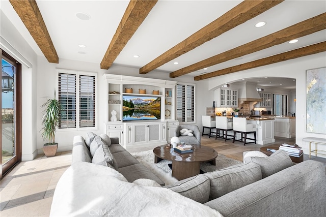 living area featuring recessed lighting, beamed ceiling, arched walkways, and baseboards