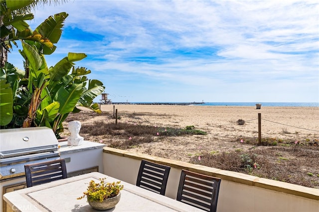 view of patio / terrace featuring outdoor dining area, a view of the beach, a water view, and area for grilling