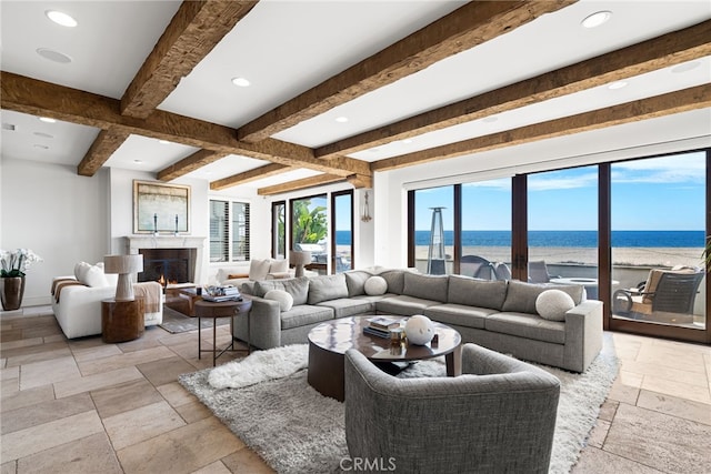 living area featuring a warm lit fireplace, stone tile flooring, beamed ceiling, and recessed lighting