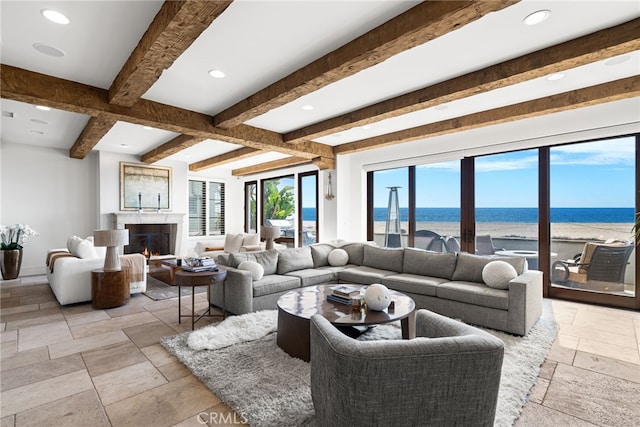 living room featuring recessed lighting, stone tile flooring, beam ceiling, and a water view