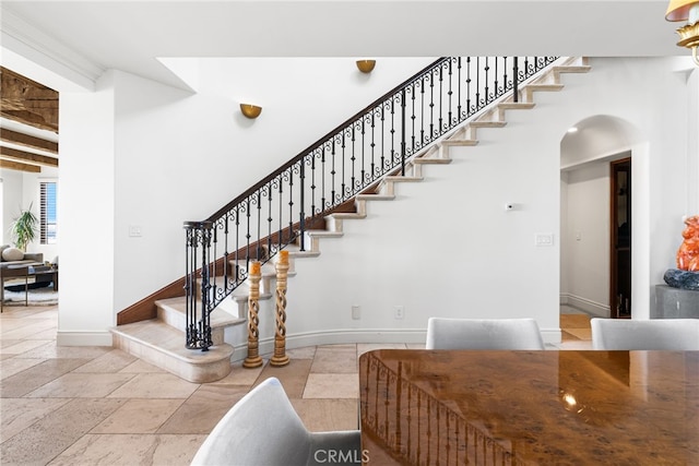 staircase featuring stone tile floors, baseboards, and arched walkways