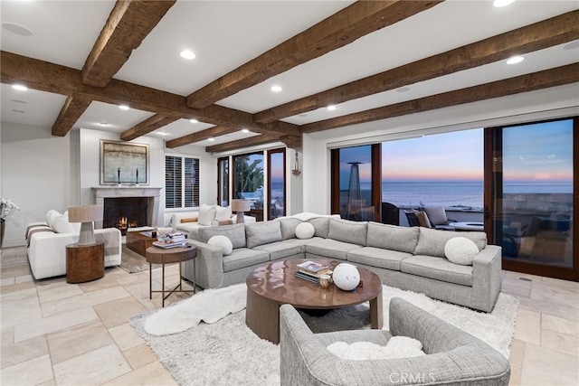 living area featuring a lit fireplace, stone tile floors, beam ceiling, and recessed lighting