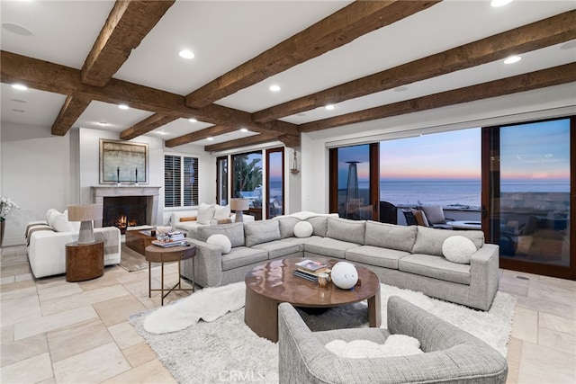 living room with stone tile flooring, beam ceiling, recessed lighting, and a warm lit fireplace
