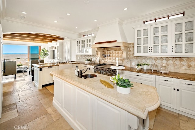 kitchen with stone tile floors, custom range hood, a sink, double oven range, and a peninsula