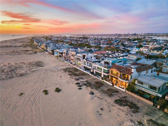 aerial view at dusk featuring a residential view and a view of the beach