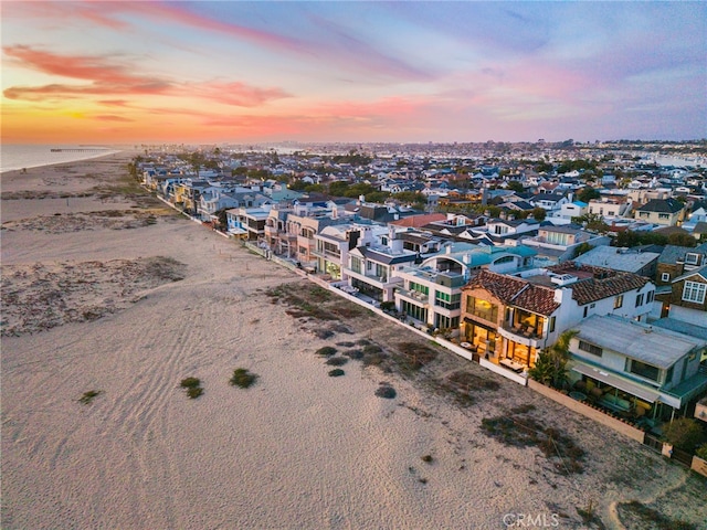aerial view at dusk with a beach view and a water view