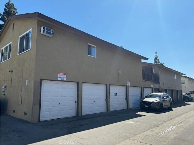 exterior space with crawl space, community garages, and stucco siding