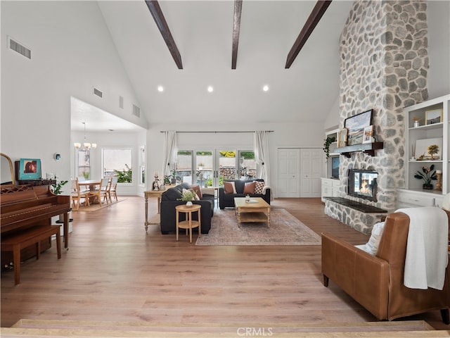 living area with beam ceiling, a fireplace, visible vents, and light wood-style floors