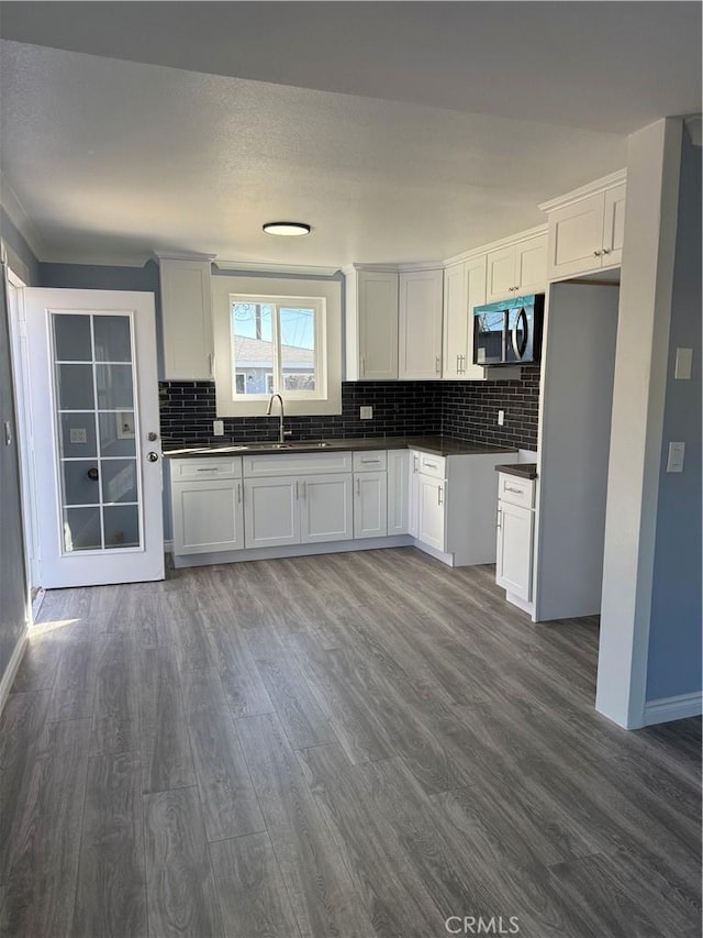 kitchen with dark countertops, stainless steel microwave, dark wood finished floors, and a sink