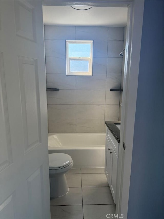 bathroom with washtub / shower combination, vanity, tile patterned flooring, and toilet