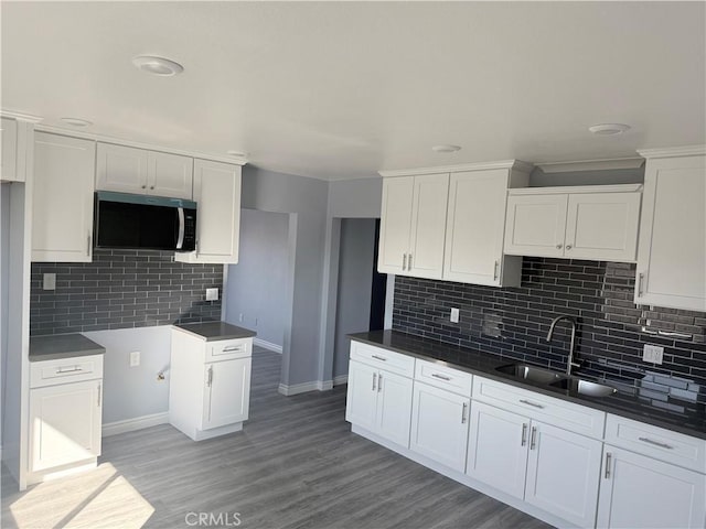 kitchen featuring dark countertops, white cabinetry, stainless steel microwave, and a sink