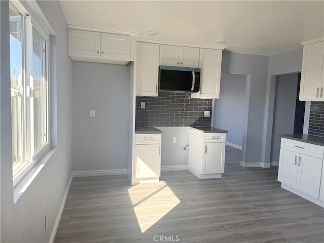 kitchen with a wealth of natural light, white cabinetry, and wood finished floors