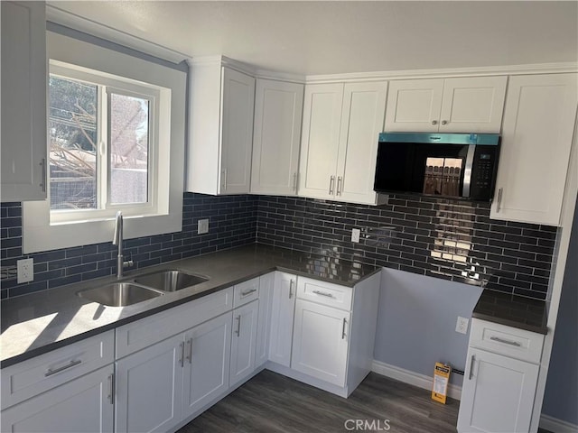 kitchen featuring white cabinetry, stainless steel microwave, tasteful backsplash, and a sink