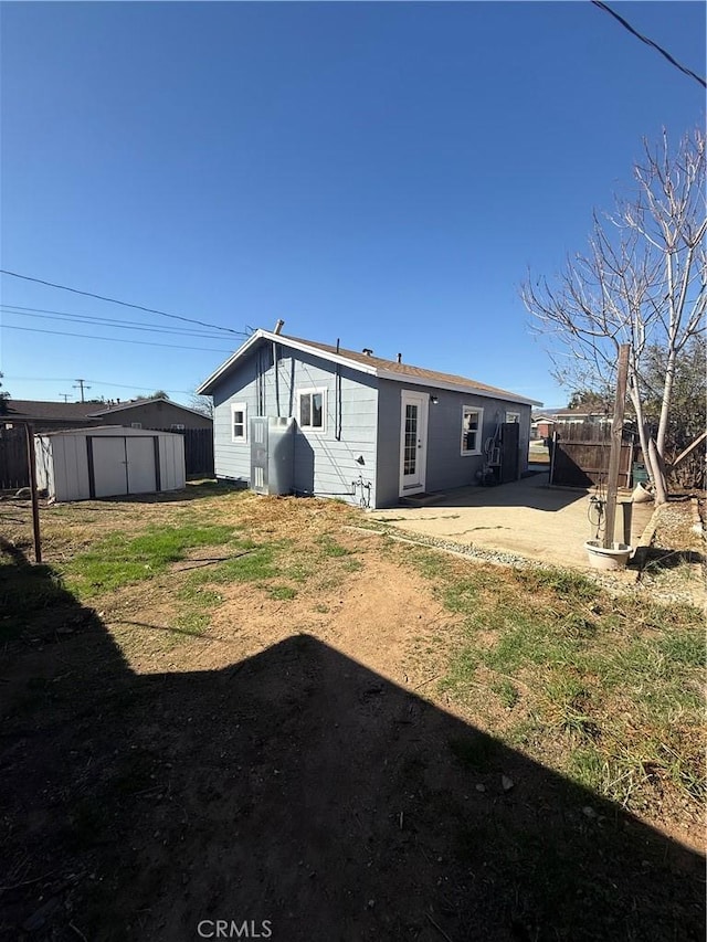 back of house with an outbuilding, a patio area, fence, and a storage unit