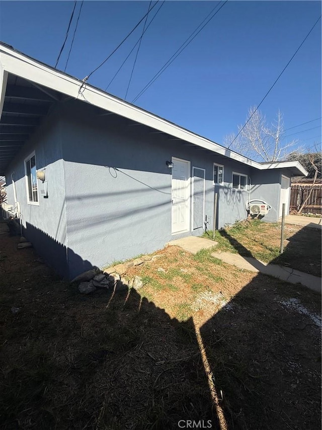 view of side of property with fence and stucco siding