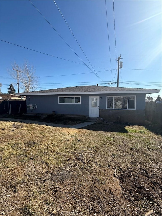 single story home with brick siding, fence, and a front lawn