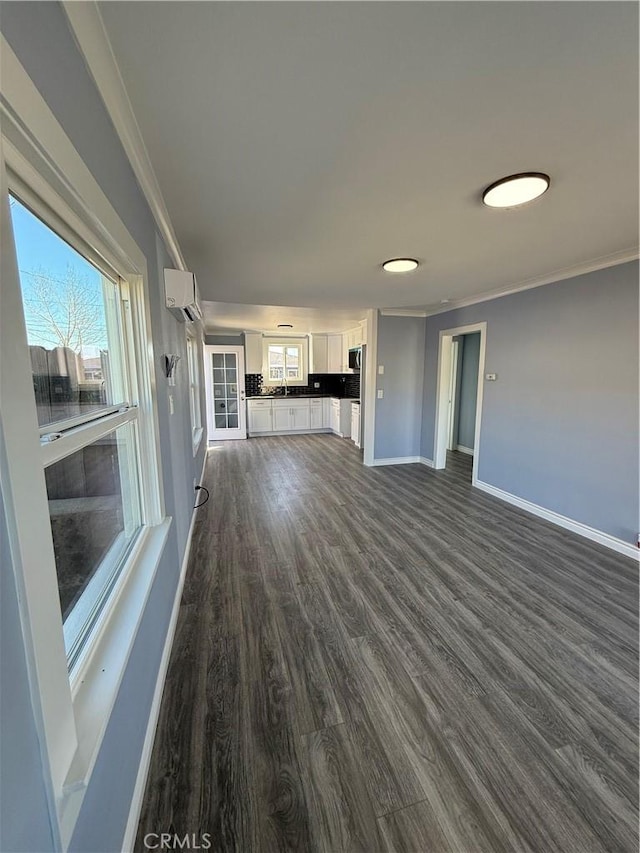 unfurnished living room with a healthy amount of sunlight, baseboards, and ornamental molding