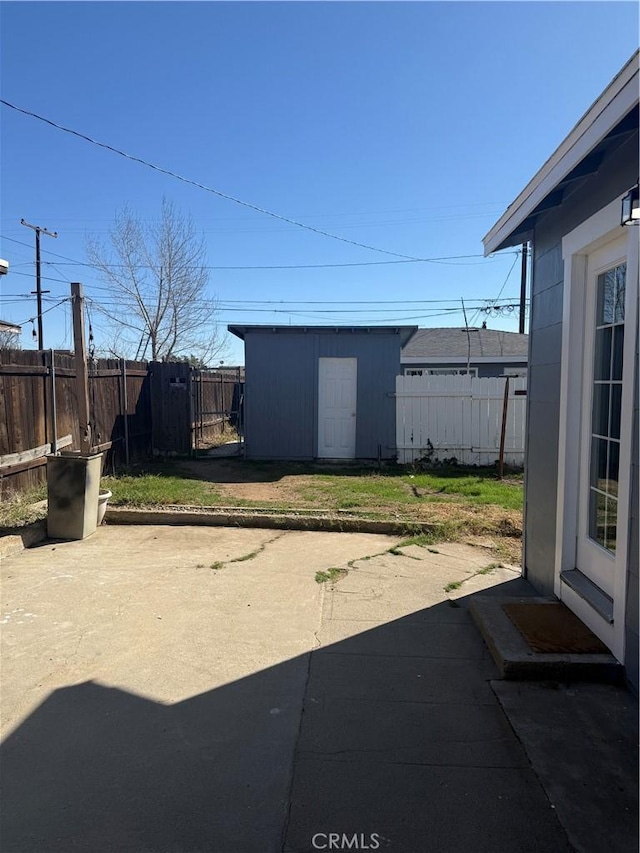 view of yard with an outbuilding, a patio, a storage shed, and a fenced backyard