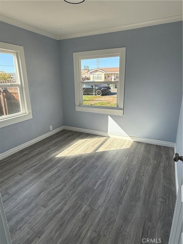 unfurnished room featuring crown molding, baseboards, and dark wood-type flooring