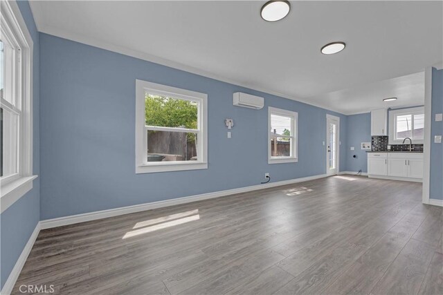 34945 Ave B, Yucaipa, CA 92399 - unfurnished living room with a sink, a wall unit AC, wood finished floors, and a healthy amount of sunlight