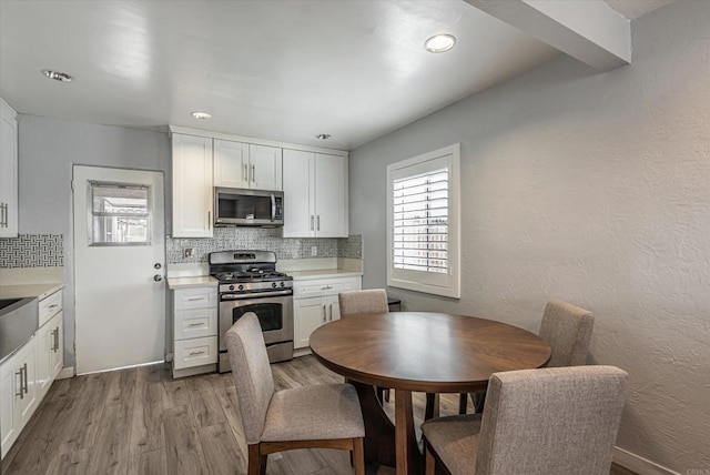 kitchen with stainless steel appliances, light countertops, light wood-style floors, and tasteful backsplash