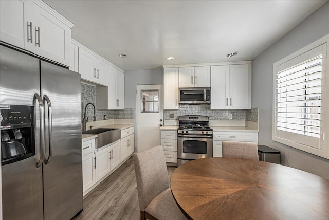 kitchen featuring stainless steel appliances, a sink, light countertops, and white cabinetry