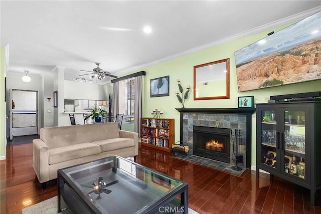 living area featuring baseboards, a tiled fireplace, wood finished floors, and crown molding