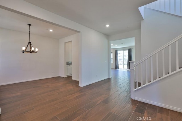 spare room featuring baseboards, dark wood finished floors, stairway, an inviting chandelier, and recessed lighting