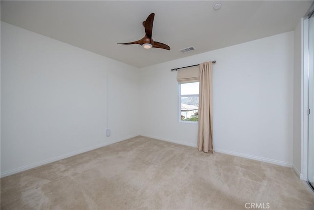 spare room with a ceiling fan, visible vents, light carpet, and baseboards