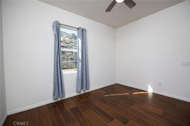 spare room with a healthy amount of sunlight, dark wood finished floors, and baseboards