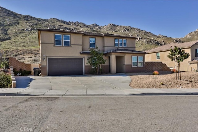 view of front of property featuring a garage, concrete driveway, a mountain view, and stucco siding