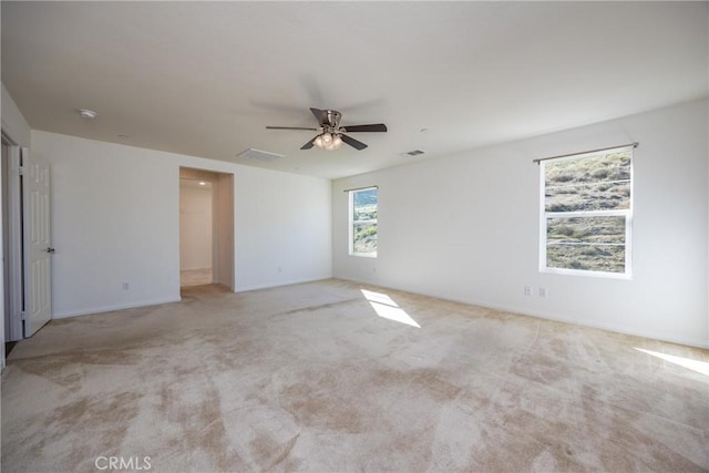 empty room featuring ceiling fan, visible vents, and light colored carpet