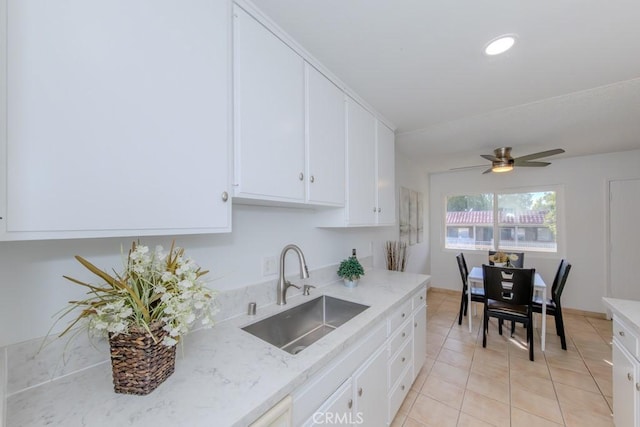 kitchen featuring light tile patterned floors, light stone counters, recessed lighting, a sink, and white cabinets