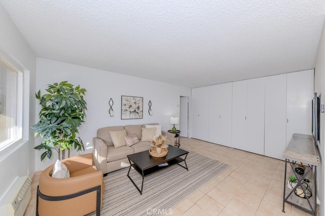 living area with a wall unit AC, light tile patterned floors, and a textured ceiling