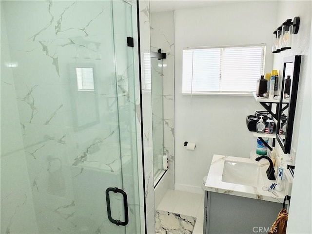 full bathroom with a marble finish shower, vanity, and baseboards