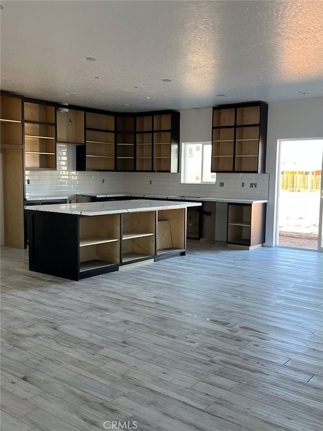 kitchen with light wood finished floors, open shelves, and decorative backsplash