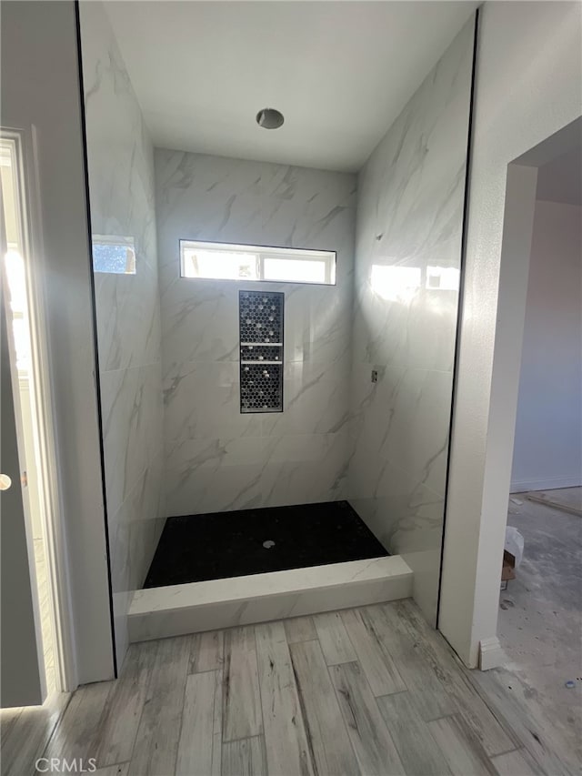 full bath featuring a marble finish shower and wood finished floors