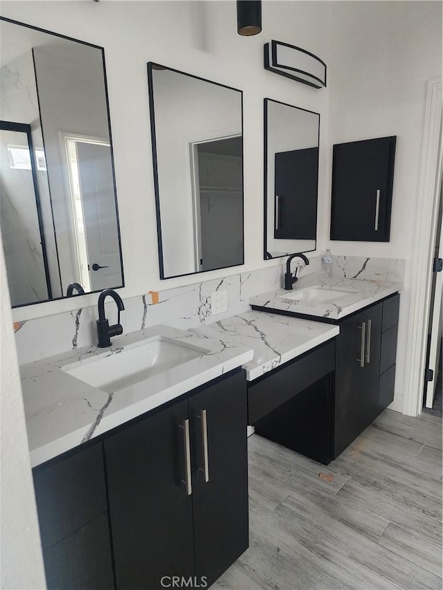 full bath with double vanity, a sink, and wood finished floors