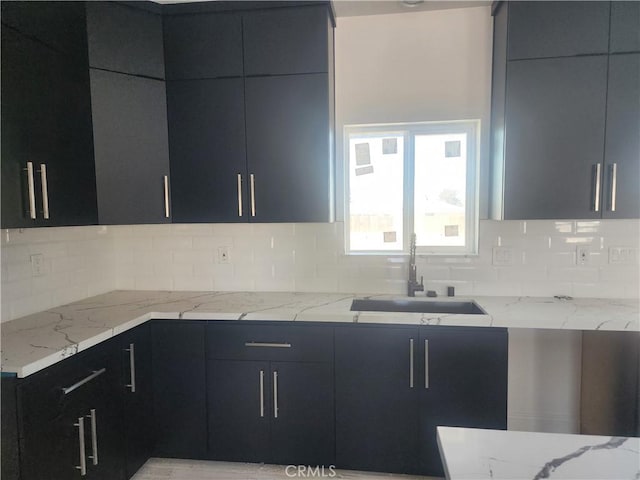 kitchen with modern cabinets, a sink, backsplash, and dark cabinets