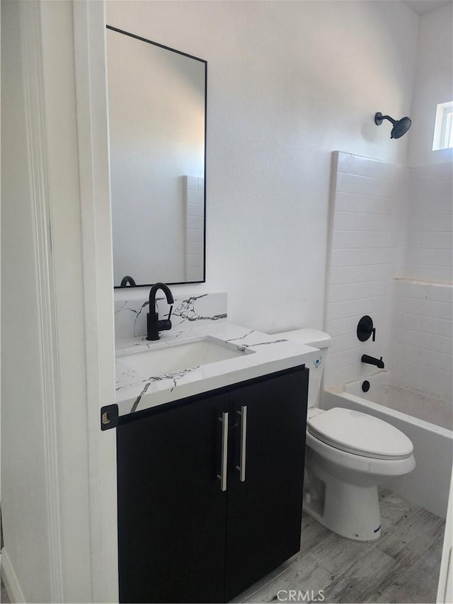 bathroom with toilet, vanity,  shower combination, and wood finished floors