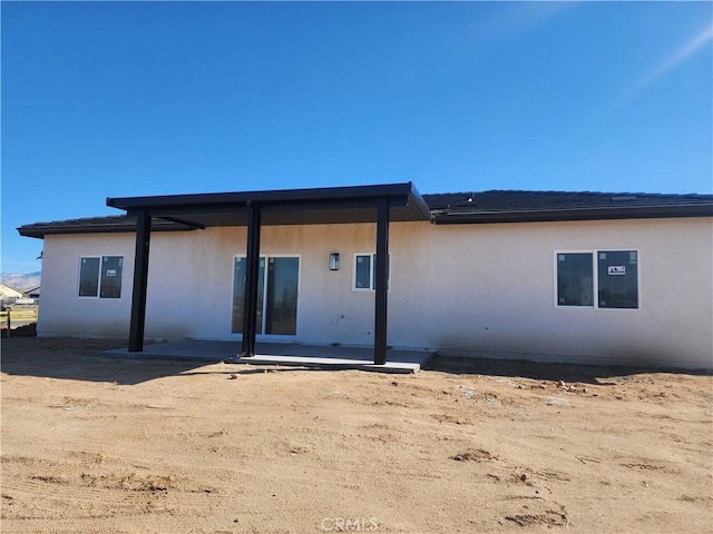 back of house with stucco siding and a patio