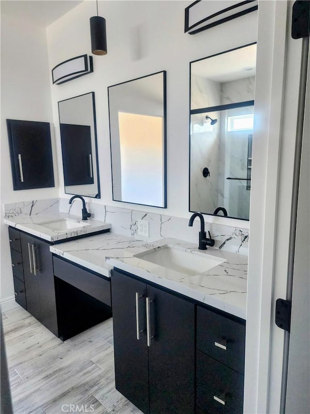full bathroom with double vanity, a sink, a shower stall, and wood finished floors