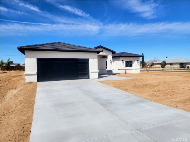 prairie-style home with a tiled roof, stucco siding, driveway, and a garage