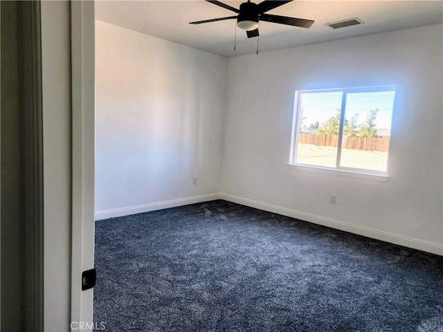 empty room featuring baseboards, visible vents, dark colored carpet, and ceiling fan