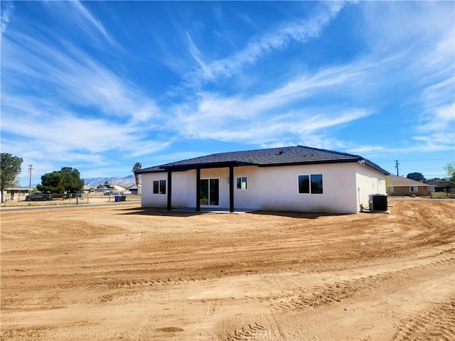 back of property with central AC unit and stucco siding