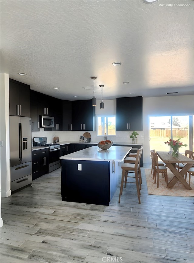 kitchen featuring light countertops, light wood-style flooring, stainless steel appliances, and dark cabinetry