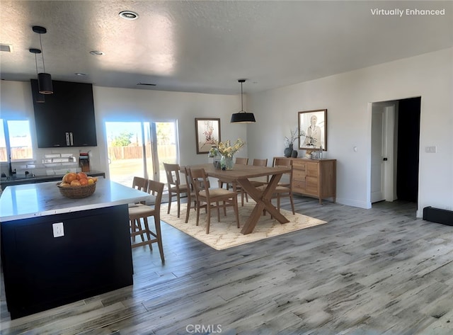 dining space with baseboards, a textured ceiling, visible vents, and light wood-style floors