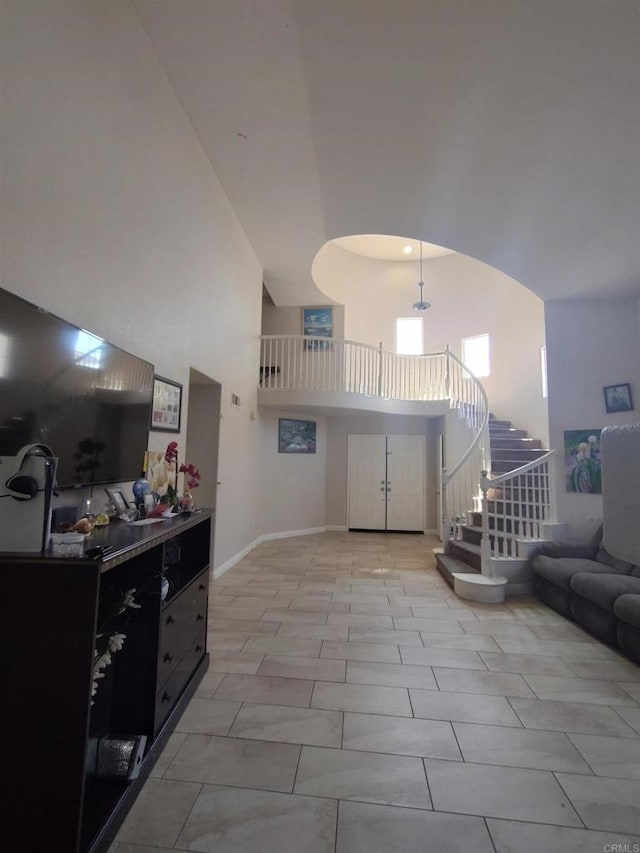 living area with stairs, a towering ceiling, and baseboards