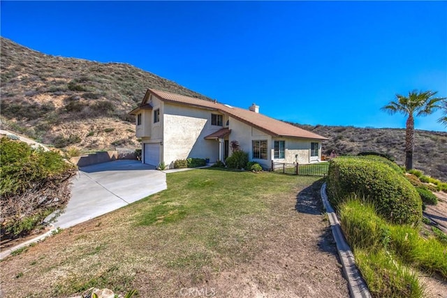 back of house with driveway, a garage, a lawn, fence, and stucco siding